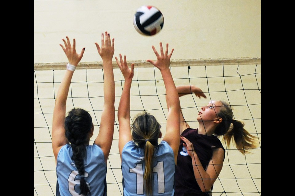 Griffin Jennie Demenuk (No. 9) rises to hit the ball past Hounds Ali L'Heureux (No. 6) and Eve Westcott (No. 11) in the senior girls city final Nov. 1 at Prince of Wales.