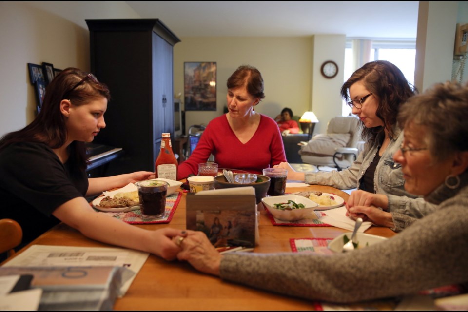 The Rev. Julie Harley, 52, center, leads a prayer with her daughters Emma, 19, left, Rachel, 21, second from right, and parishioner Ann Armstrong, right, who prepared the lunch meal.