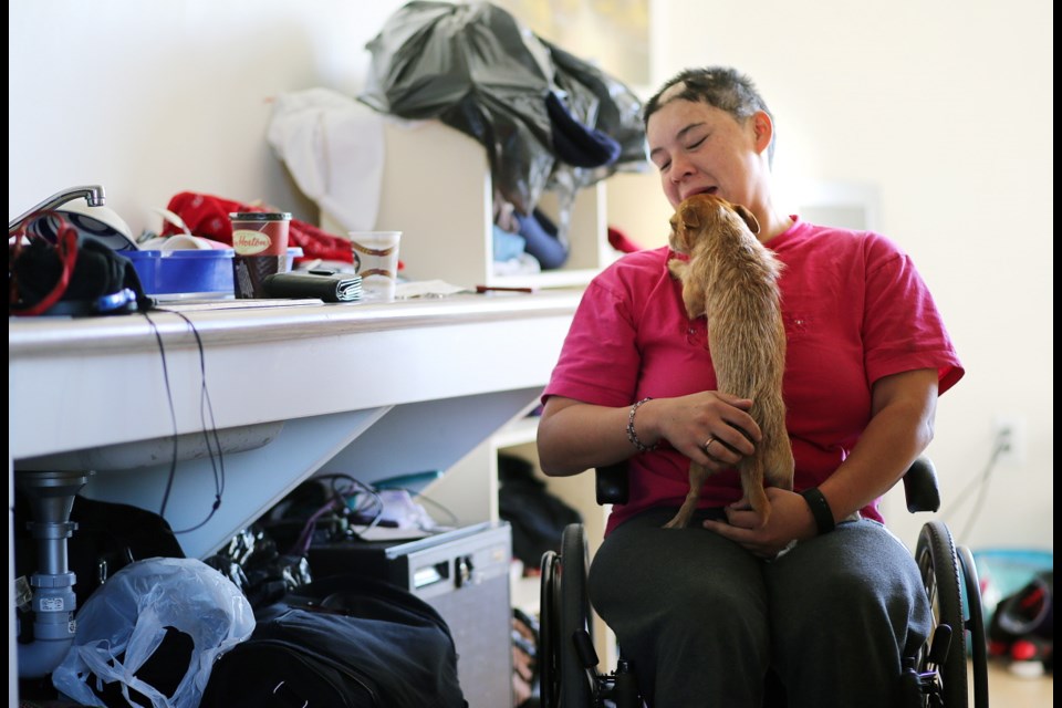 Sherri-Lynn Crocker gives her dog, Tre, a hug in her room at Rock Bay Landing in Victoria.