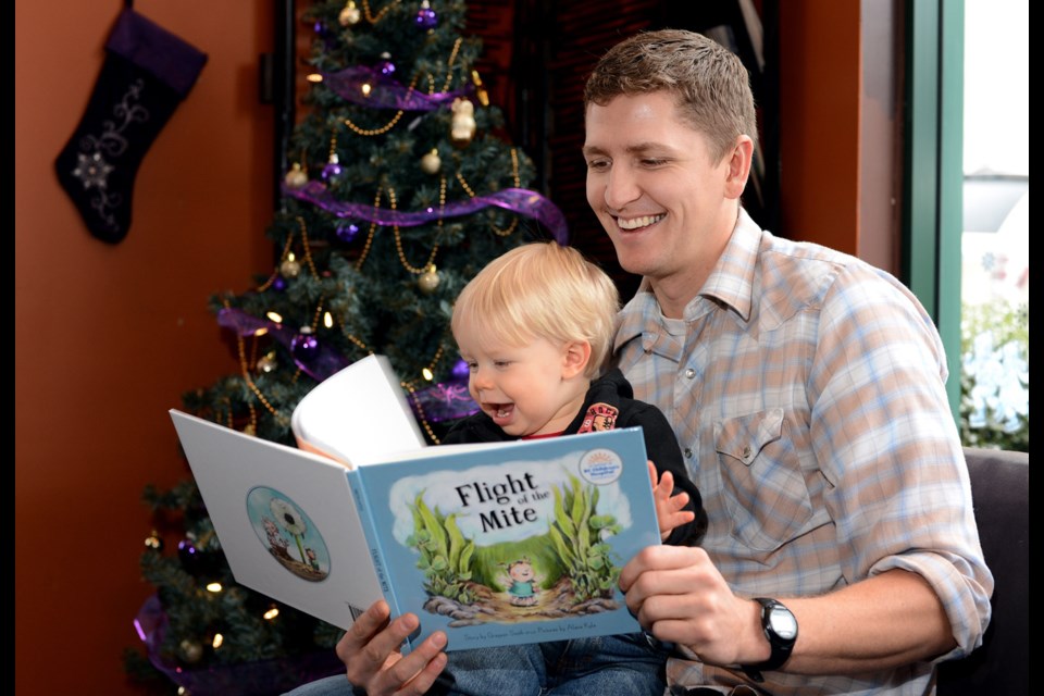 Grayson Smith reads to his almost-one-year-old son, Josiah, from his new book, Flight of the Mite.