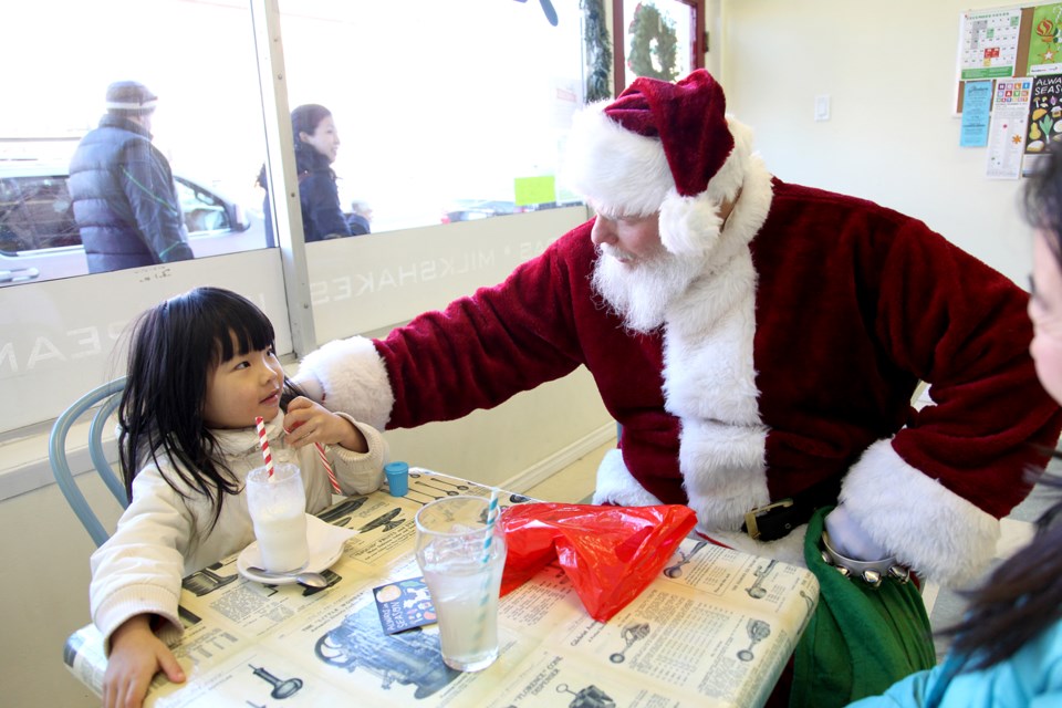 Santa visits with Rachel Ma at the Glenburn Soda Fountain and Confectionery Shop before the Light Up the Heights event.