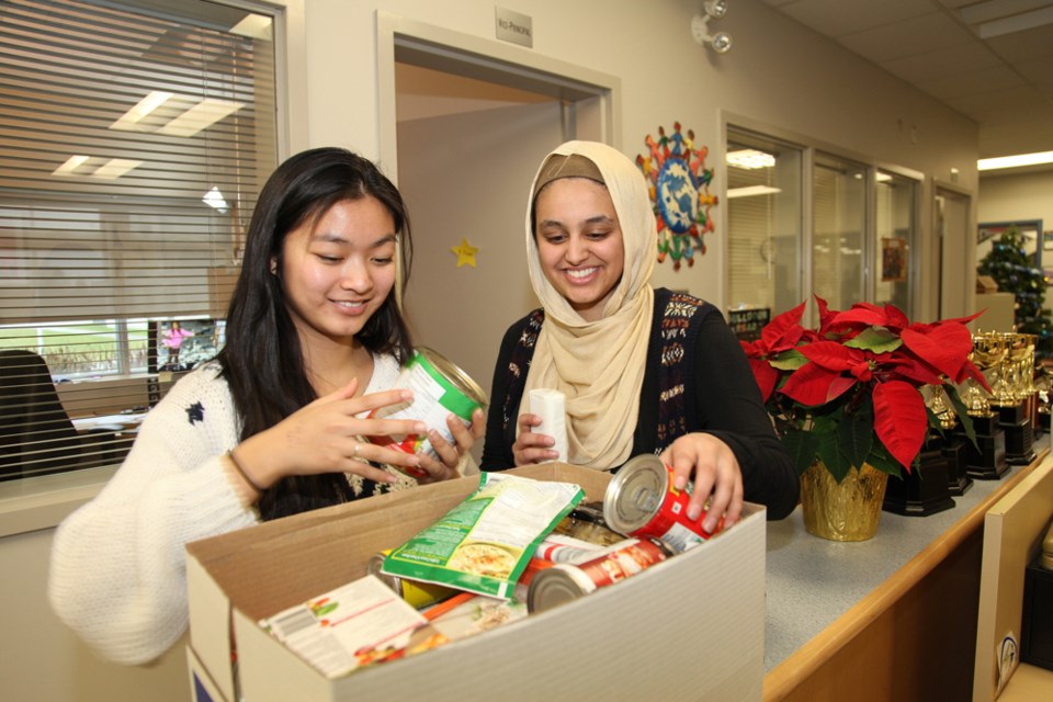 Nhi Nguyen and Zahra Haq filling hampers at Byrne Creek Secondary. The annual hamper drive makes sure students from low-income families receive extra help at Christmas.