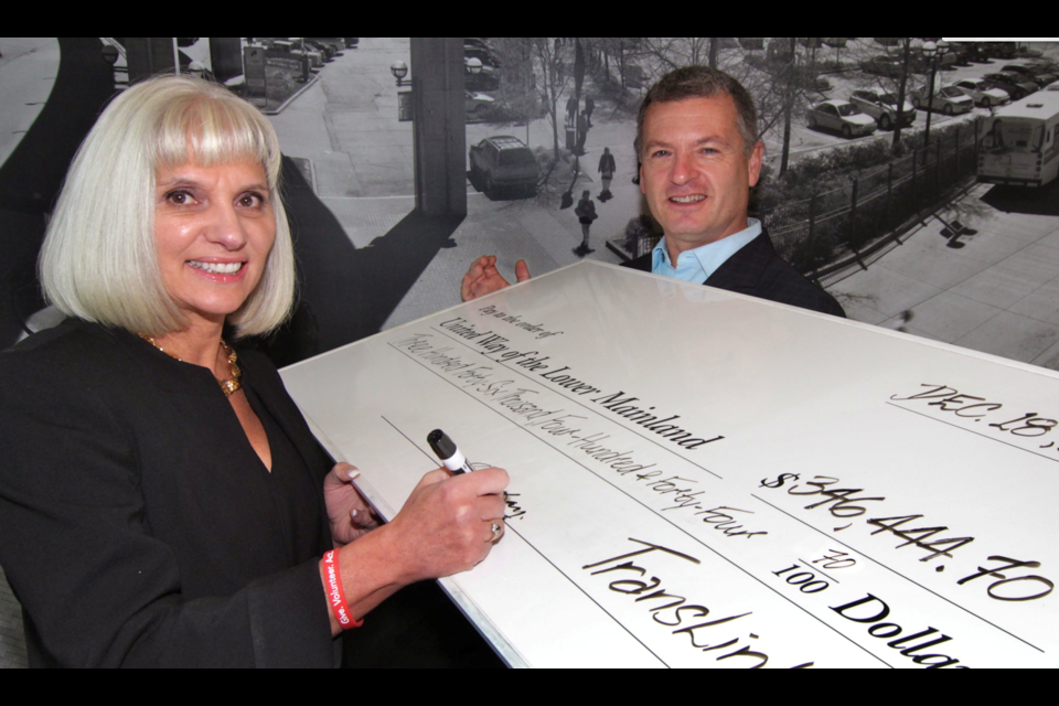 Translink CFO Cathy McLay signs over a Christmas cheque for $346,444.70 in support of United Way programs and services to president and CEO Michael McKnight.
