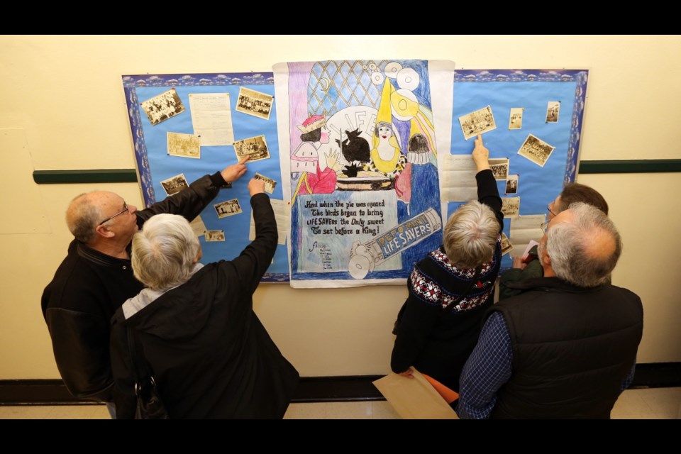 Oaklands Elementary School celebrates its centennial this year. Event includes classrooms filled with archival photos, historic displays and games from each decade. People checking out old class photos in the hallways.