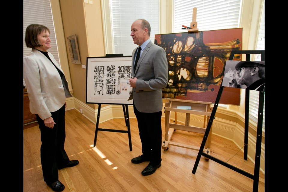 Ruth Wittenberg, chairwoman of the Art Gallery of Greater Victoria, and gallery director Jon Tupper display a couple of paintings by Anthony Thorn, whose portrait is on the easel at right.