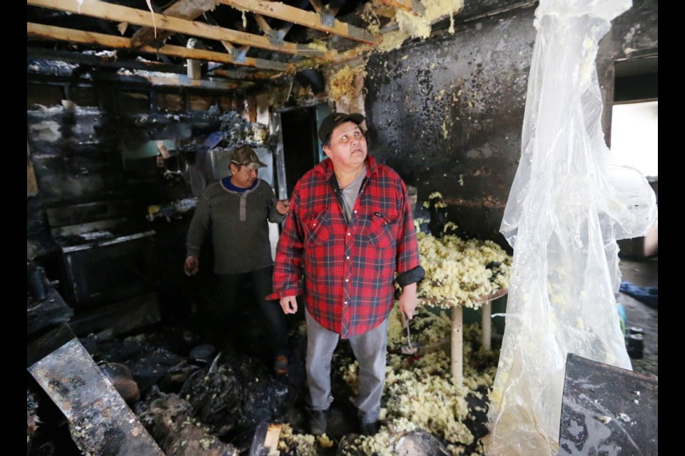 Maurice Tom, left, and Ralph Henry look over the damage caused by a fire last week at a house on the Pauquachin First Nation. The homeowners did not have insurance, but the family of 16 is thankful everyone survived.