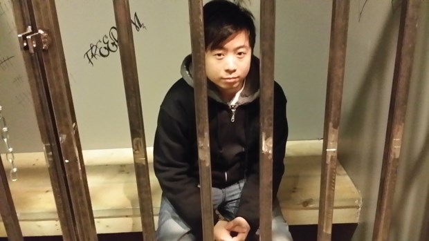 Justin Tang, owner/operator of Exit, sits in one of his themed escape rooms, a jail cell.
