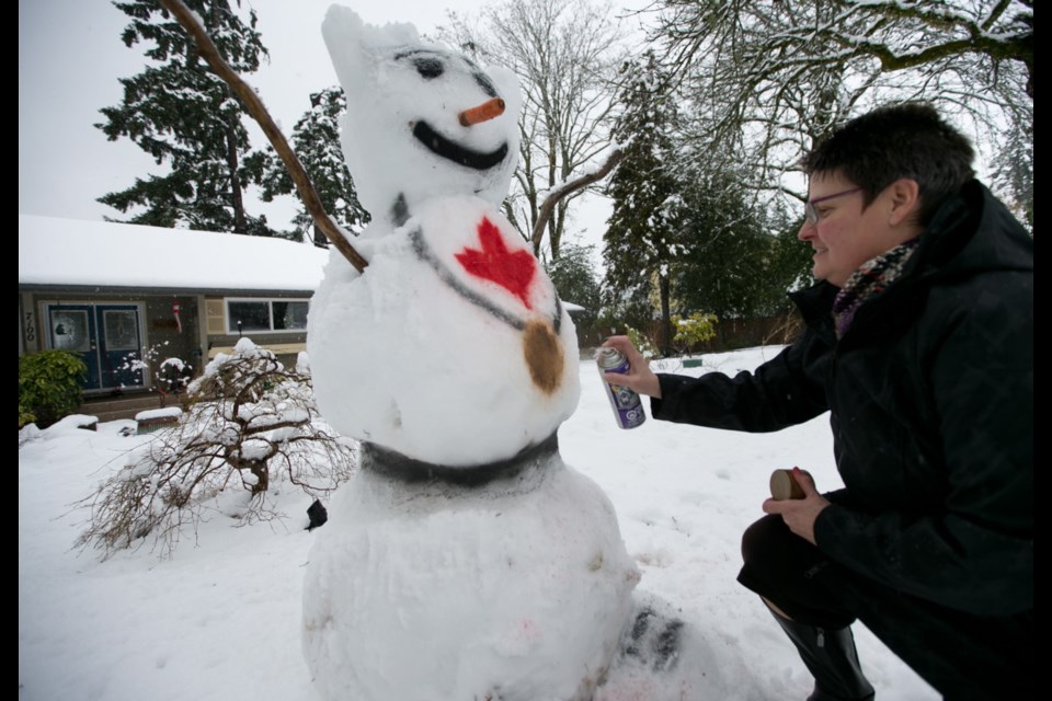 Monday: Allison Humphreys touches up the family's snowman made by her husband Tom, son Benn and grandchildren Isaac, 7, and Sarah, 3, in front of their house on Hagan Road to celebrate Canadian Olympic victories.