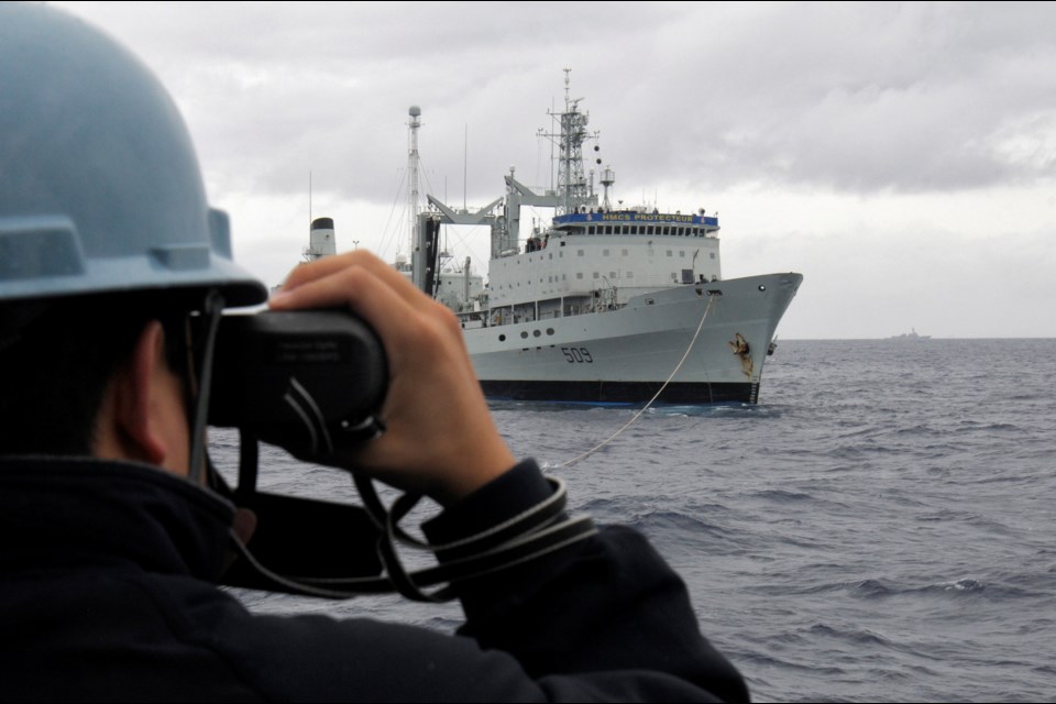 A sailor aboard American guided-missile cruiser USS Chosin (CG 65) observes the Royal Canadian Navy’s HMCS Protecteur during a towing operation on Saturday, March 1, 2014. Protecteur's engineer room was heavily damaged in a fire on Thursday.