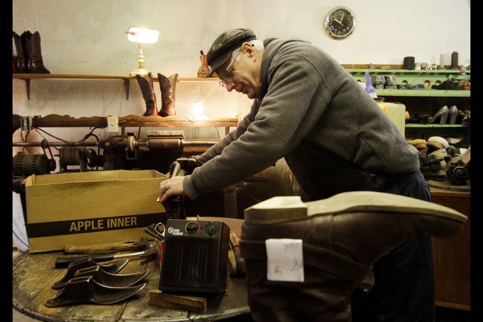 Mike Waterman stitches a sheepskin slipper, using tools that would have been at home in his shop 50 years ago.