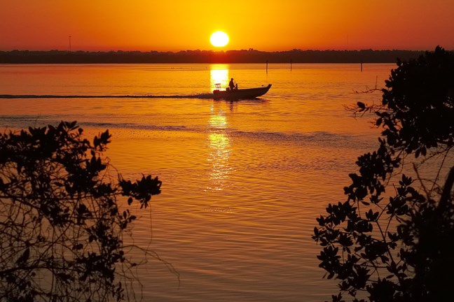 A boater cruises at sunrise near Bonita Springs, Fla., where temperatures in the area are expected to reach 80 degrees, Tuesday morning, March 4, 2014. (AP Photo/J. David Ake)