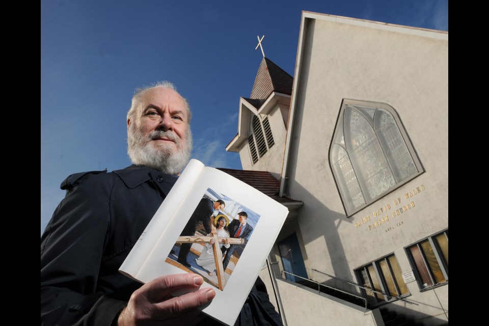 Anthony Norfolk holds a copy of one the paintings from the Stations of the Cross series painted by artist Chris Woods at St. David of Wales church. photo Dan Toulgoet