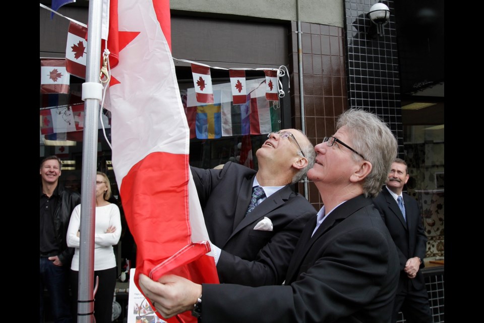 LYLE STAFFORD, TCVictoria Mayor Dean Fortin, left, hoists the flag with Flag Shop owner Paul Servos on Friday.