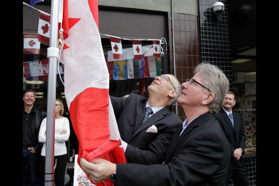 LYLE STAFFORD, TC
Victoria Mayor Dean Fortin, left, hoists the flag with Flag Shop owner Paul Servos on Friday.