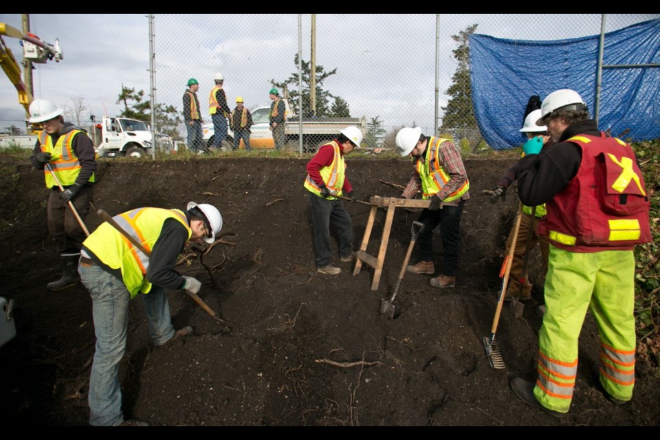 Workers sift through soil from a field at Craigflower Elementary School on Tuesday.