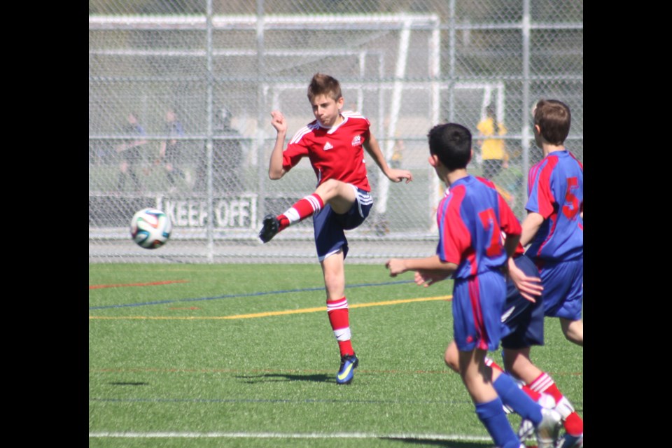 Ryan Roberts, in red, kicks the ball during a semifinal game against West Vancouver.