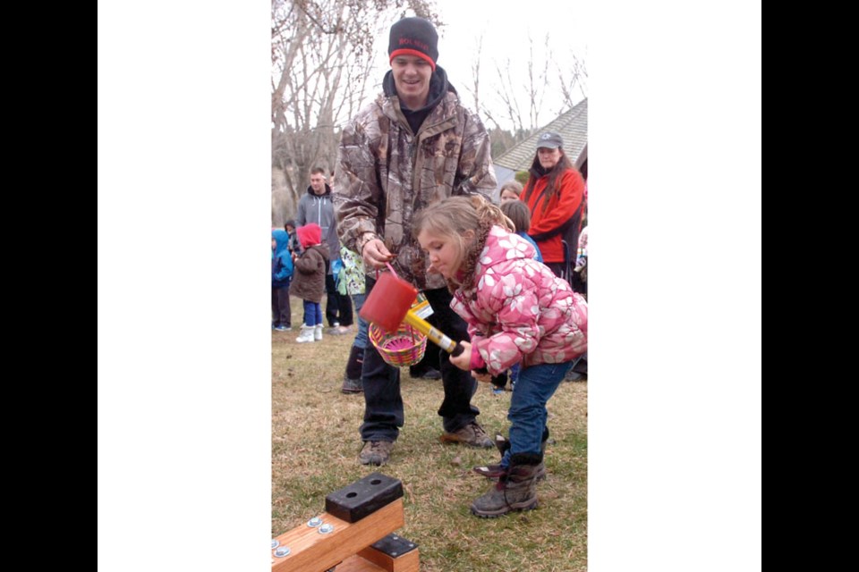 Julia Gillis, 5, keeps her eye on the target as she rings the bell. Dad Steve coaches.