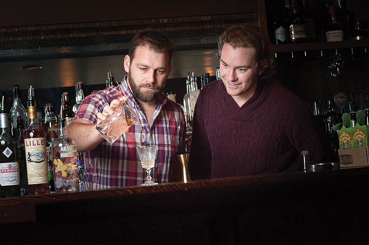 Mike Graziano (right) watches as Jacob Sweetapple pours the finishing touchs on The Burlesque Beauty Queen, a cocktail Sweetapple invented to celebrate the start of Graziano’s record-setting quest to travel to every country in the world before the age of 30. Rob Newell photos