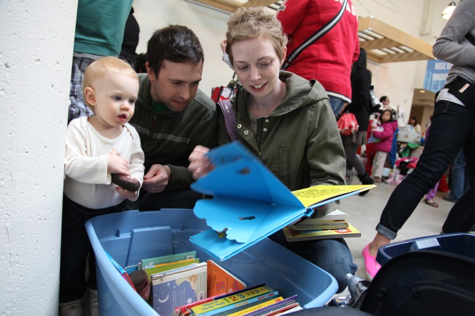 Jonathan Blasberg, along with daughter Emily and wife Sabrina, checks out some books at the Kids Swap Meet April 27 at the River Market.