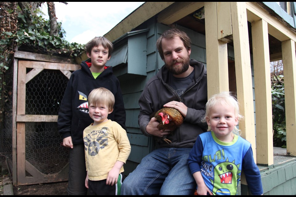 Gone afowl: Haydn, left, Reason, Dan Perry and Keen with the hen they're fostering. Perry's wife, Paula Cole, heard about the bird from a neighbour who knocked on her door to see if the hen was one of theirs. It wasn't, but the family is keeping it until the mystery owner is found.