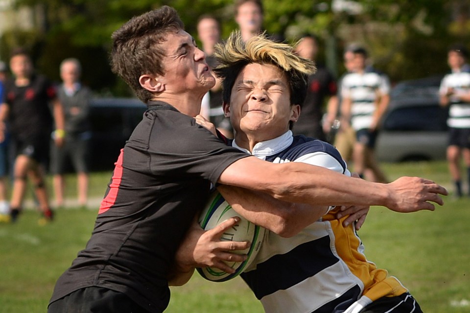 Magee captain Sean Hase (in black) collides with Kitsilano's Ryan Lu April 28 at Camosun Park in a senior boys rugby city semifinal. The Magee Lions won 17-15.