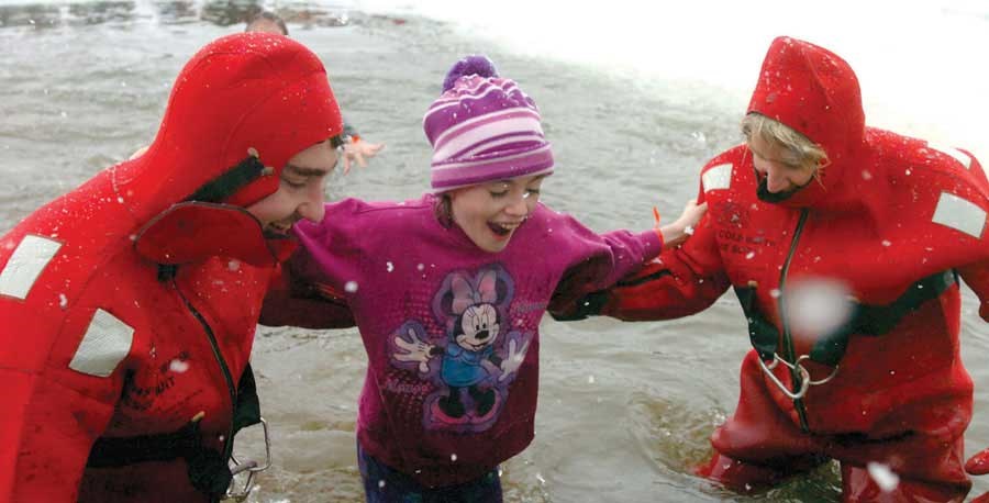 Averil Harris, left, and Carolyn Davenport, from the Ness Lake Volunteer Fire Department, help Jaelynn Joly, 12, from the frigid Ness Lake water during the camp's annual Polar Bear Dip.