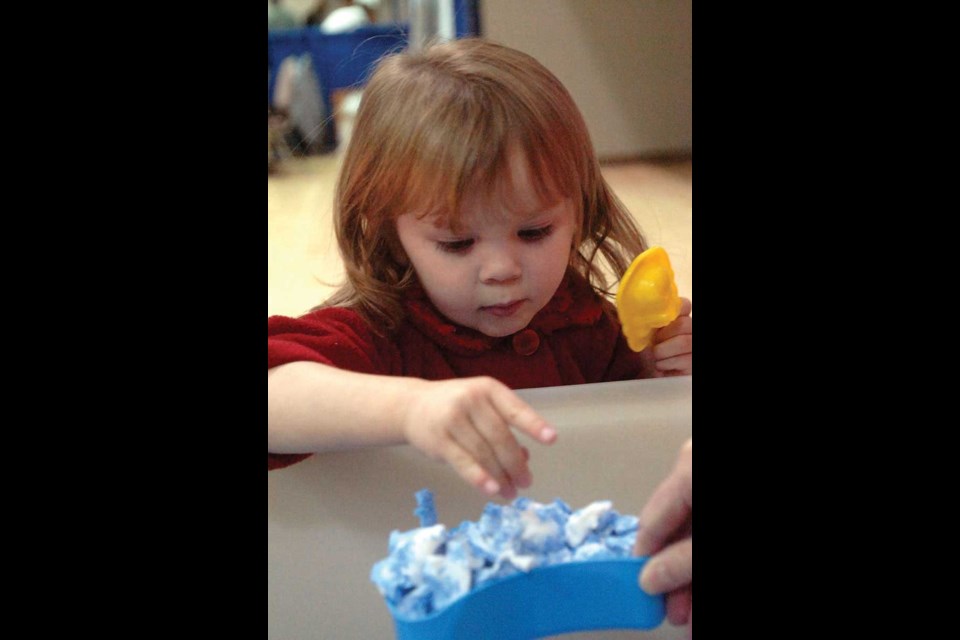 Two-year-old Summer Edge was interested in the Moon Sand at the YMCA booth.