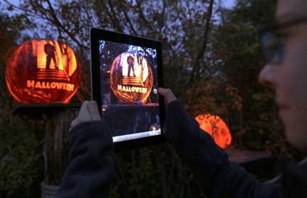 A girl uses her iPad to photograph a pumpkin carved with the theme of the movie "Halloween" while viewing illuminated jack o' lanterns at the Roger Williams Park Zoo in Providence, R.I., Monday, Oct. 8, 2012. Some 5,000 carved pumpkins are on display for this yearÃ­s Jack-oÃ­-lantern Spectacular, one of the nationÃ­s largest jack-oÃ­-lantern shows. (AP Photo/Charles Krupa)