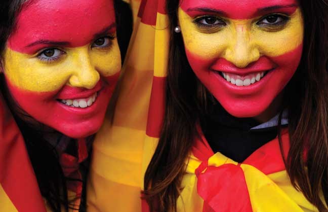 Two girls with their faces painted with the colours of the Spanish flag pose to photographers during the holiday known as Dia de la Hispanidad, Spain's National Day in Barcelona, Spain, Friday, Oct. 12, 2012. Spain is in recession and under pressure to fix its finances while celebrating the day Christopher Columbus discovered America in the name of the Spanish Crown. (AP Photo/Manu Fernandez)