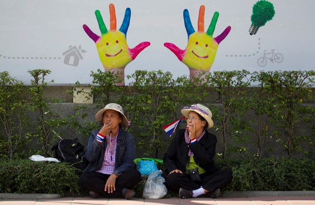 Thai anti-government protesters blow whistles while waiting for the arrival of their colleagues during a rally outsides the government complex in Bangkok, Thailand Monday, Jan. 13, 2014. Anti-government protesters took over key intersections in Thailand's capital Monday, halting much of the traffic into Bangkok's central business district as part of a months-long campaign to thwart elections and overthrow the democratically elected prime minister. (AP Photo/Wason Wanichakorn)