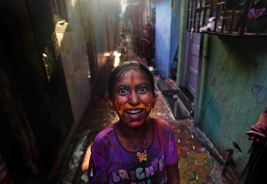 An Indian girl, her face smeared with colored powder, reacts to the camera during Holi celebrations in Mumbai, India, Thursday, March 8, 2012. Holi, the Hindu festival of colors, also heralds the coming of spring. (AP Photo/Rafiq Maqbool)