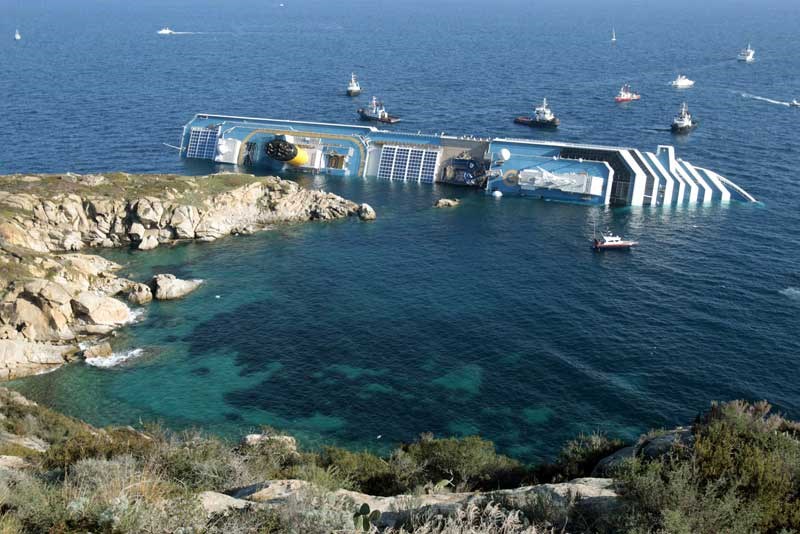 The luxury cruise ship Costa Concordia leans on its side after running aground in the tiny Tuscan island of Giglio, Italy, Saturday, Jan. 14, 2012.   The luxury cruise ship ran aground off the coast of Tuscany, sending water pouring in through a 160-foot (50-meter) gash in the hull and forcing the evacuation of some 4,200 people from the listing vessel early Saturday, the Italian coast guard said.  The number of dead and injured is not yet confirmed Coast Guard Cmdr. Francesco Paolillo said. (AP Photo/Gregorio Borgia)