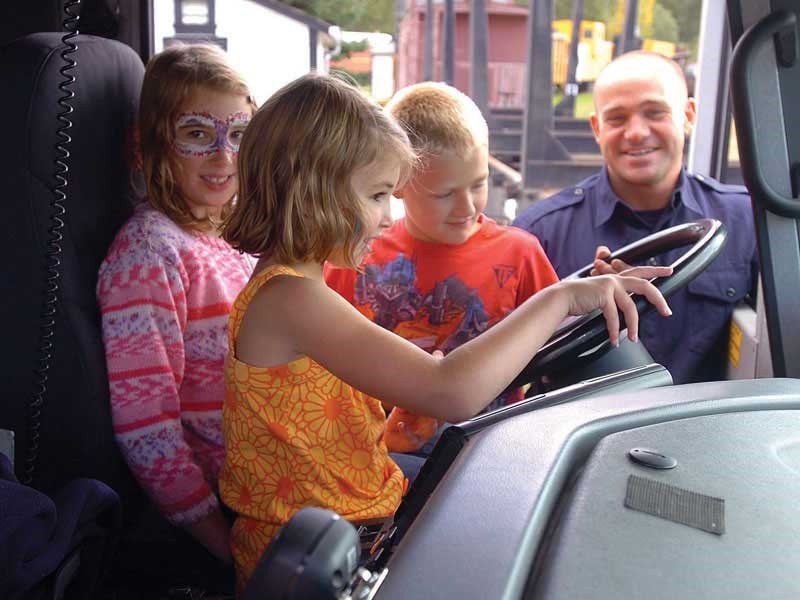 Emily Tassie, 8, left, sister Hannah, 6, Batai Forsythe, 8, and Prince George Firefighter Kevin Thorne, had fun in the cab of the fire engine.Citizen photo by David Mah