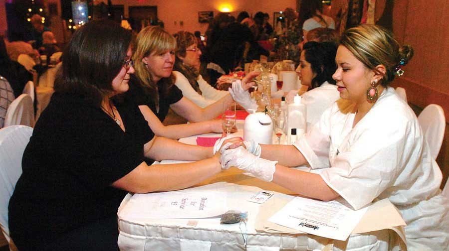 Trisha Stewart, right, gives Erin Mould a hand massage at the Ms. Lorea's booth at the Girl Friends Who Care fashion show.
