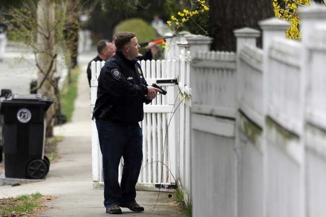 A police officer with is weapon drawn conducts a search for a suspect in the Boston Marathon bombings, Friday, April 19, 2013, in Watertown, Mass. The two suspects in the Boston Marathon bombing killed an MIT police officer and hurled explosives at police in a car chase and gun battle overnight that left one of them dead and his brother on the loose, authorities said Friday as thousands of officers swarmed the streets in a manhunt that all but paralyzed the Boston area. (AP Photo/Matt Rourke)