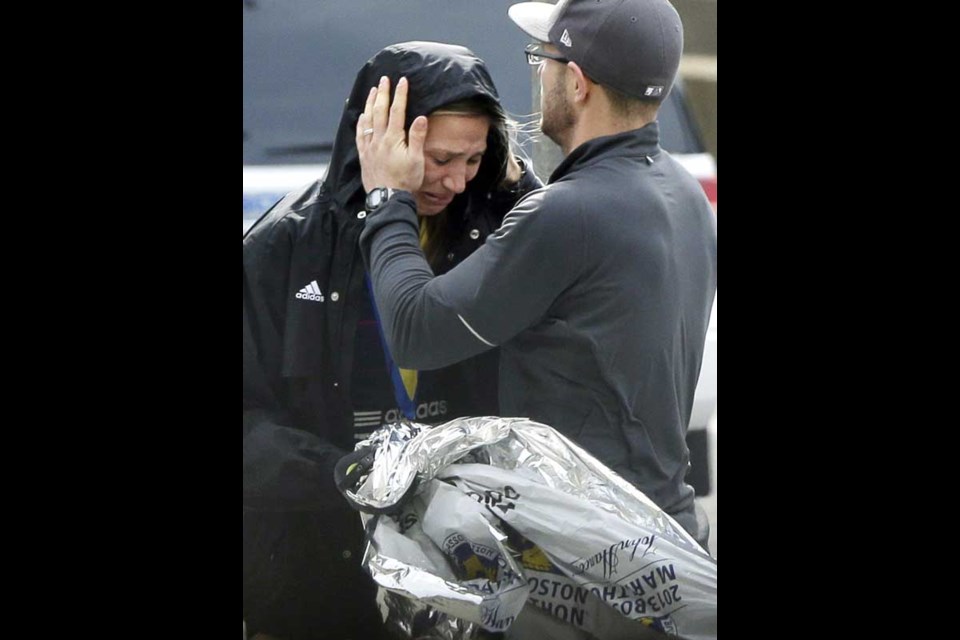 An unidentified Boston Marathon runner is comforted as she cries in the aftermath of two blasts which exploded near the finish line of the Boston Marathon in Boston, Monday, April 15, 2013. (AP Photo/Elise Amendola)