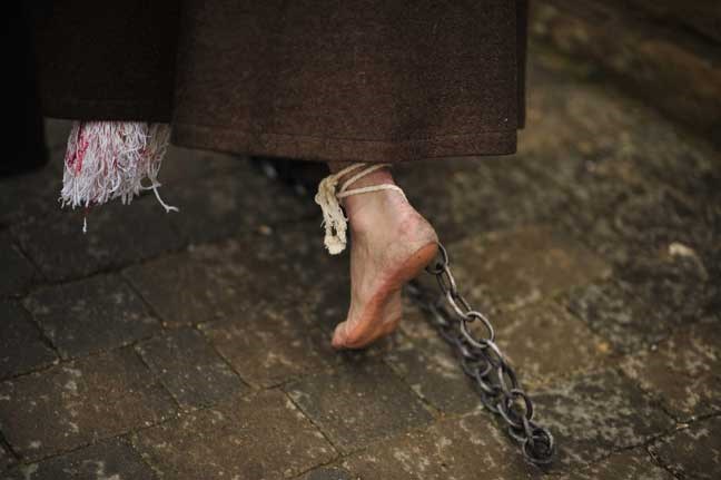 A foot with a chain of a masked penitent from La Santa Vera Cruz brotherhood, seen as he walks walks along the way taking part in an Easter procession known as 'Los Picaos' in the small village of San Vicente de la Sonsierra, northern Spain on Friday, March 29, 2013. Penitents, or disciplinants, take part on the procession lashing themselves as an act of faith and penance, a tradition dating from the early 16th century.(AP Photo/Alvaro Barrientos)