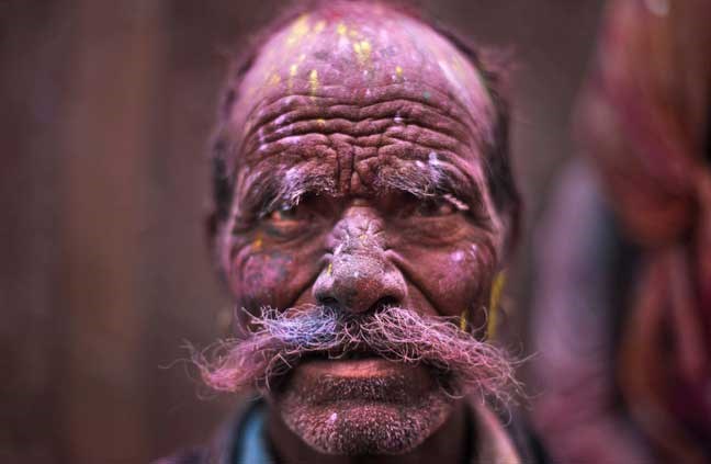 A Hindu devotee, face smeared with colored powder, leaves the Banke Bihari temple during Holi celebrations in Vrindavan, India, Wednesday, March 27, 2013. Holi, the Hindu festival of colors that also marks the advent of spring, is being celebrated across the country Wednesday. (AP Photo/Altaf Qadri)