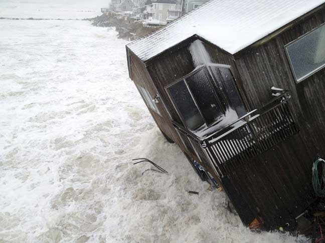 A house on the Plum Island seacoast in Newbury, Mass., sits partially collapsed into the churning surf, driven by winds from a slow-moving storm centered far out in the Atlantic Ocean, at high tide Friday morning, March 8, 2013. The storm dropped up to a foot of snow in some parts of New England, caused coastal flooding in Massachusetts and slowed the morning commute in the region to a slushy crawl. (AP Photo/Newburyport Daily News, Mac Cerullo)