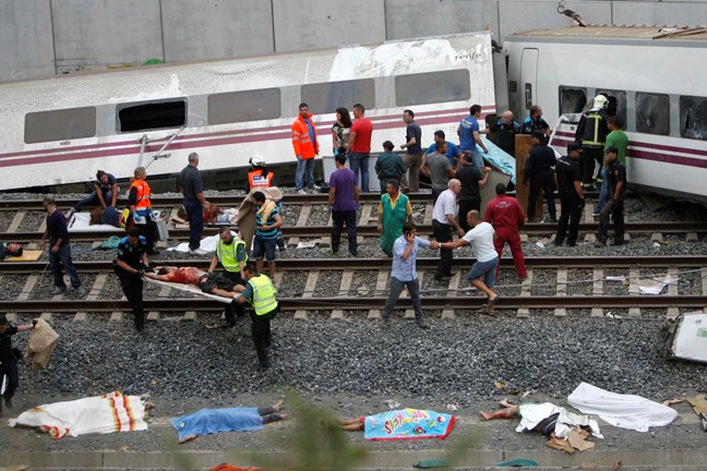 Emergency personnel respond to the scene of a train derailment in Santiago de Compostela, Spain, Wednesday, July 24, 2013. A train derailed in northwestern Spain on Wednesday night, toppling passenger cars on their sides and leaving at least one torn open as smoke rose into the air. Dozens were feared dead, with possibly even more injured. (AP Photo/ El correo Gallego/Antonio Hernandez)