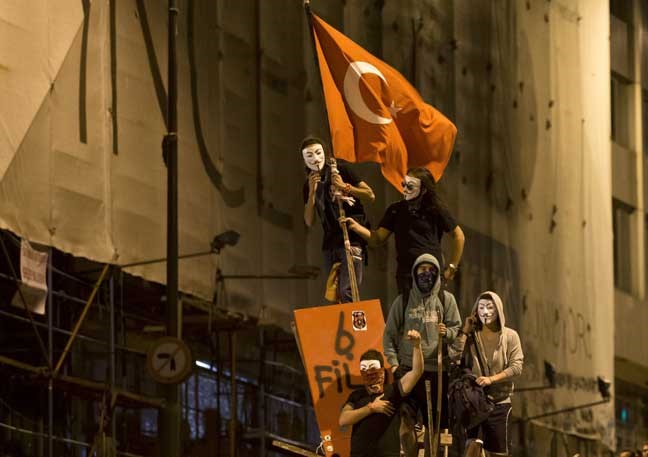 Protesters wearing Guy Fawkes masks stand on a barricade on a road leading to Taksim Square early Sunday, June 9, 2013. Tens of thousands of people thronged Istanbul's Taksim Square Saturday, and thousands more turned out in central Ankara as protests that have presented Turkish Prime Minister Recep Tayyip Erdogan with the first serious challenge to his leadership entered their second week. (AP Photo/Vadim Ghirda)