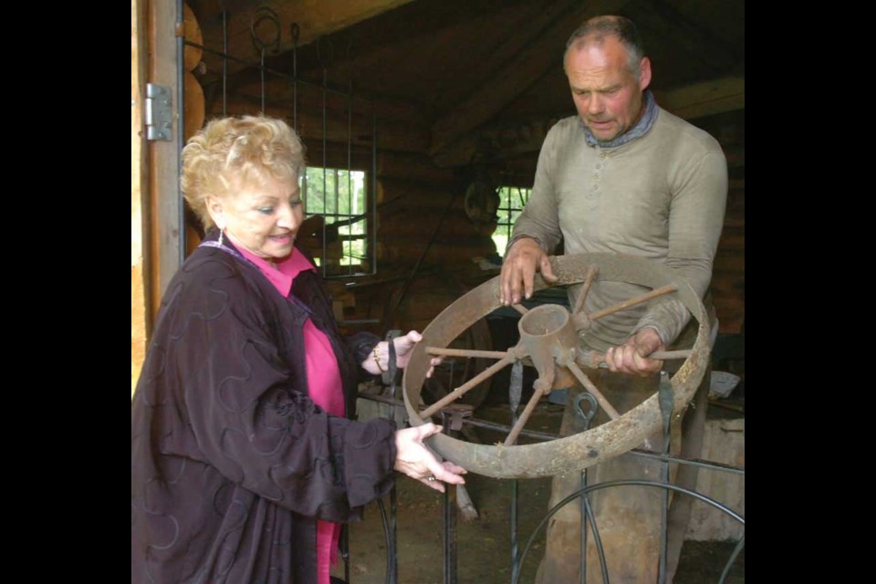 Blacksmith Mike Hardeman shows Lorea Reimer an old wagon wheel.