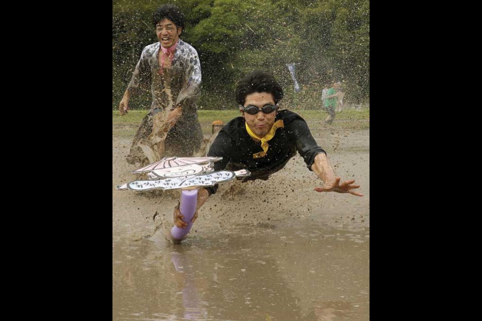 A competitor grabs a flag in a rice paddy during a sports festival in Sasayama, western Japan Saturday, June 1, 2013. (AP Photo/Kyodo News) JAPAN OUT, MANDATORY CREDIT