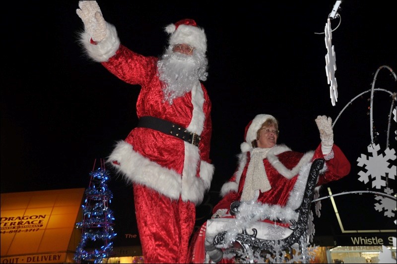 Santa Claus and Mrs. Claus greet 鶹residents lined up on the street.