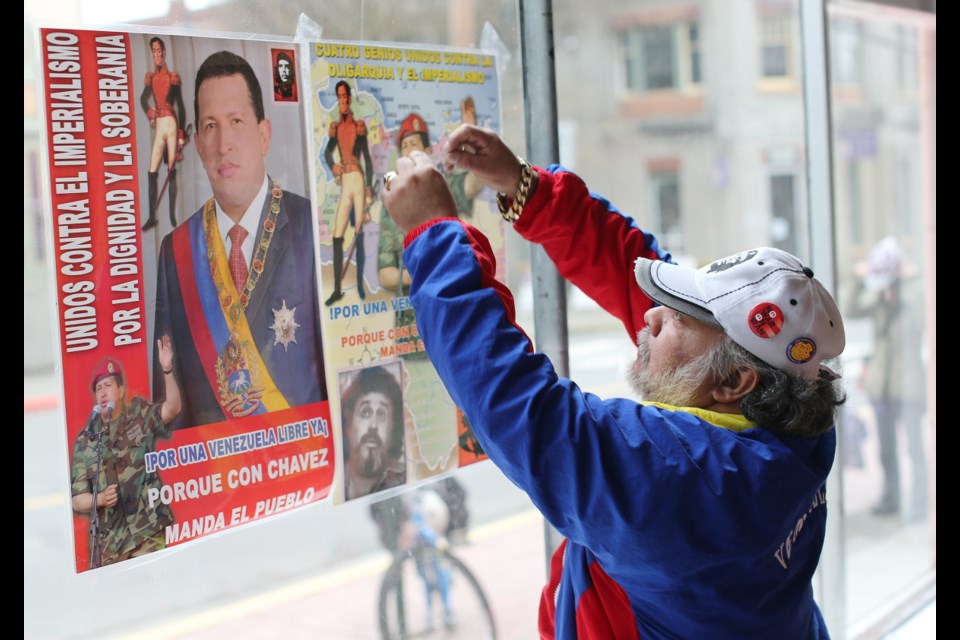 Mario Mendoza hangs a poster as the Victoria Central America Support Committee and the Salvadorean Farabundo Marti Committee hold a memorial gathering to pay homage to the memory of Venezuelan President Hugo Chavez at the Fernwood Community Centre on Sunday.
