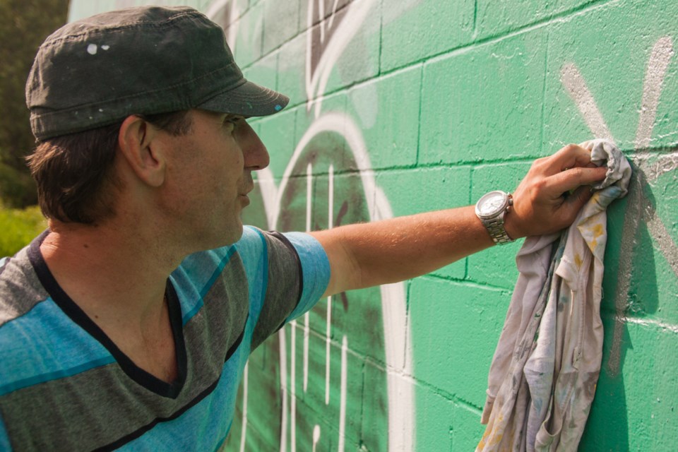 Todd Polich scrubs away some of the graffiti that appeared overnight on three of his murals in Burnaby. Taggers targeted murals sometime Sunday night near the Royal Oak SkyTrain station.
