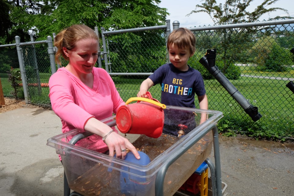 Teacher Jenny Lee and student Henry Thomson, 3, (not the Henry in the story) play in one of the preschool's new water tables. Photography By Larry Wright.