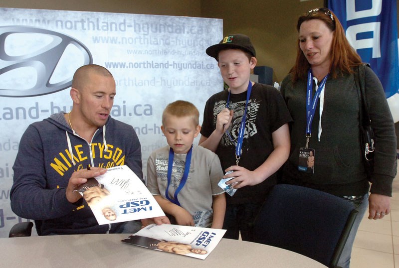 Georges St. Pierre signs photos for Dominic Piper, 7, Kyle Piper, 13, and Mindy Leckay.