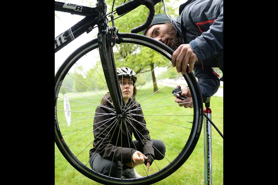 Bike mechanic Richard Machhein works on Sadia Badiei’s front tire at the Bike to Work Week maintenance station set up at the corner of 37th and Ontario. Photo Dan Toulgoet