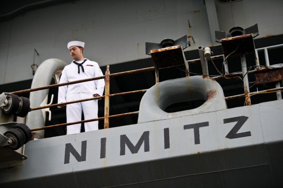 A U.S. sailor watches arrivals aboard the USS Nimitz on Saturday.